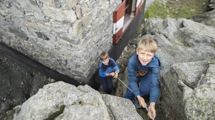 Ein Junge übt Klettern am Felsen und wird von unten gesichert | © DAV / Jens Klatt