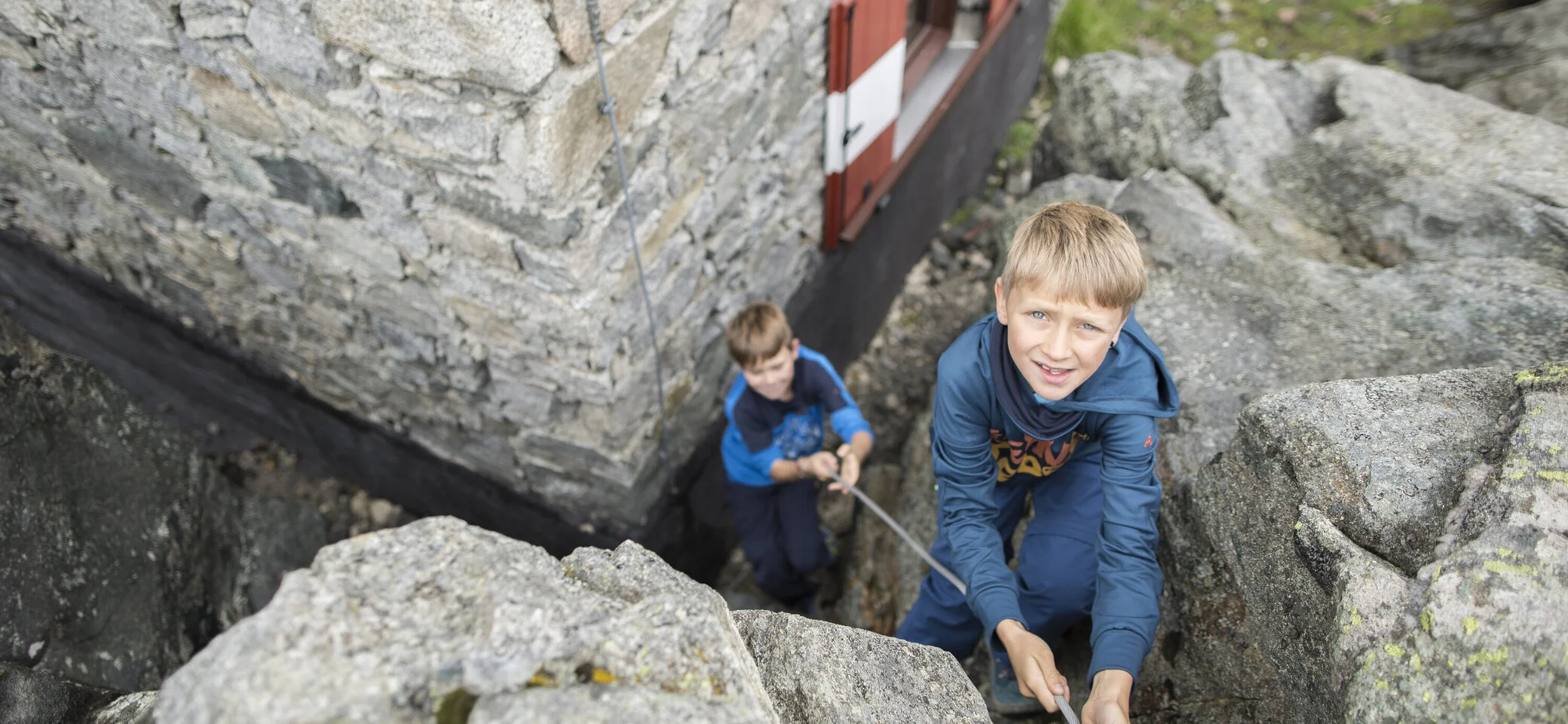 Ein Junge übt Klettern am Felsen und wird von unten gesichert | © DAV / Jens Klatt